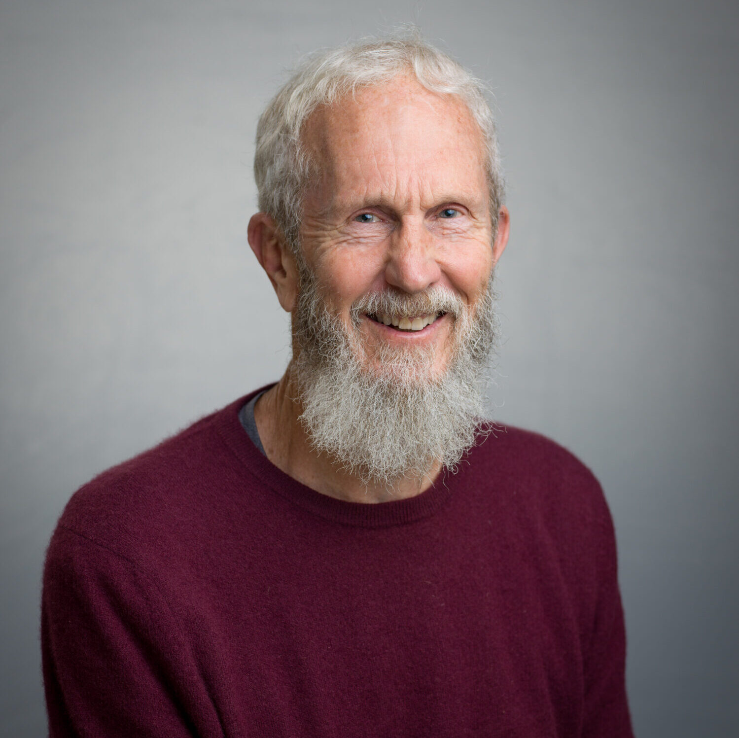 JDF-19thJune2024-0081 A man with a white hair and full white beard smiles at the camera. He is wearing a dark-coloured jumper.