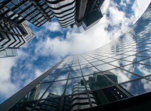 A view of the sky with clouds looking up between tall buildings.